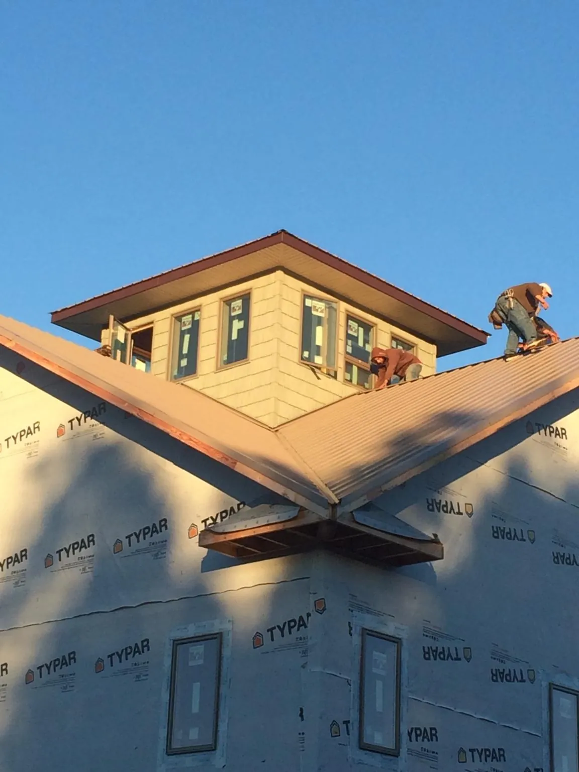 Roofers working around a rooftop cupola on a new metal roof at sunset — Roof Waterproofing in Glen Dale by Roofing Brothers